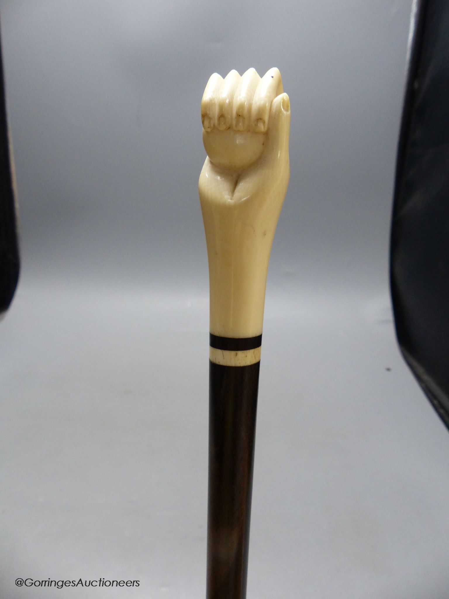 A rosewood and ivory handled walking stick in the form of a hand holding a ball